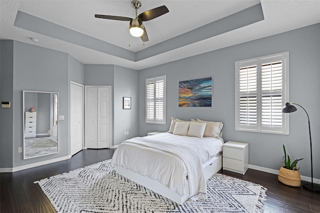 11337 Via Andiamo, Windermere, FL 34786 - bedroom featuring a tray ceiling, dark wood-type flooring, and a ceiling fan