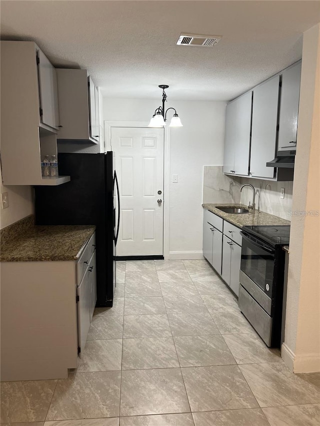 767 Willie Mays Pkwy, Orlando, FL 32811 - kitchen featuring electric stove, freestanding refrigerator, dark stone countertops, under cabinet range hood, and a chandelier