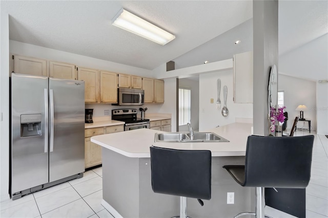 2979 Viscount Cir, Kissimmee, FL 34747 - kitchen with appliances with stainless steel finishes, lofted ceiling, light brown cabinetry, a peninsula, and a kitchen bar