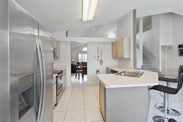 2979 Viscount Cir, Kissimmee, FL 34747 - kitchen featuring appliances with stainless steel finishes, vaulted ceiling, a peninsula, light countertops, and a kitchen breakfast bar