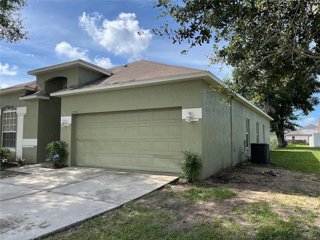 7714 Tanbier Dr, Orlando, FL 32818 - view of side of property with stucco siding, concrete driveway, an attached garage, and a shingled roof