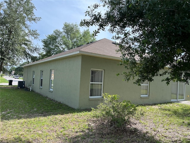 7714 Tanbier Dr, Orlando, FL 32818 - view of side of property featuring stucco siding, a lawn, and a shingled roof
