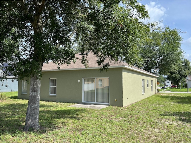 7714 Tanbier Dr, Orlando, FL 32818 - rear view of property featuring stucco siding and a yard