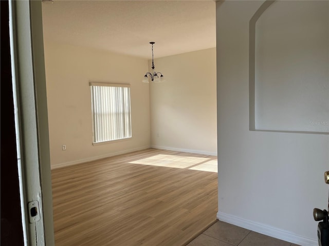 7714 Tanbier Dr, Orlando, FL 32818 - unfurnished room with a chandelier, arched walkways, and light wood finished floors