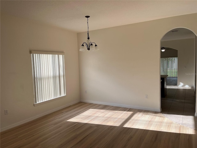 7714 Tanbier Dr, Orlando, FL 32818 - unfurnished dining area with arched walkways, wood finished floors, and a chandelier