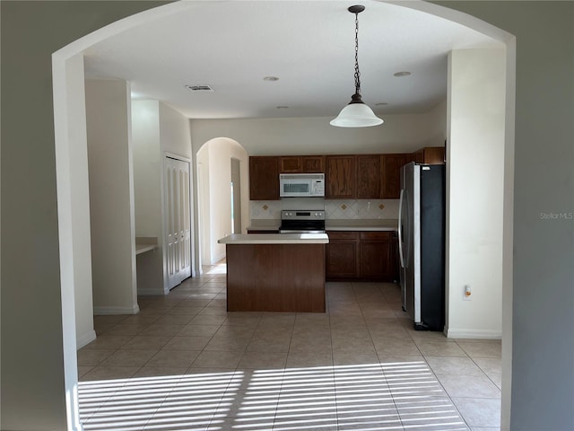 7714 Tanbier Dr, Orlando, FL 32818 - kitchen with appliances with stainless steel finishes, light countertops, arched walkways, a center island, and decorative backsplash