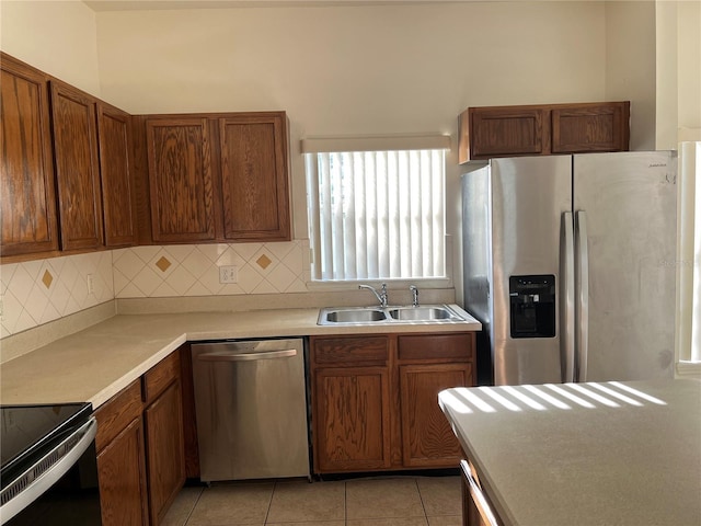 7714 Tanbier Dr, Orlando, FL 32818 - kitchen with stainless steel appliances, decorative backsplash, light tile patterned flooring, and brown cabinets