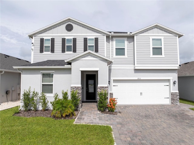2813 Sanctuary Dr, Clermont, FL 34714 - view of front of home featuring board and batten siding, a garage, decorative driveway, and stone siding