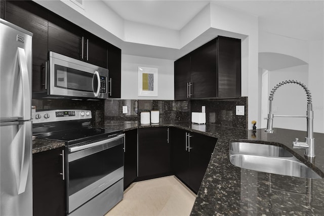 7350 Westpointe Blvd Unit 215, Orlando, FL 32835 - kitchen featuring stainless steel appliances, dark cabinetry, dark stone countertops, and backsplash