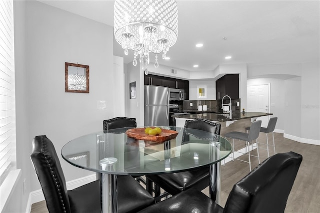 7350 Westpointe Blvd Unit 215, Orlando, FL 32835 - dining area featuring arched walkways, wood finished floors, a chandelier, and recessed lighting
