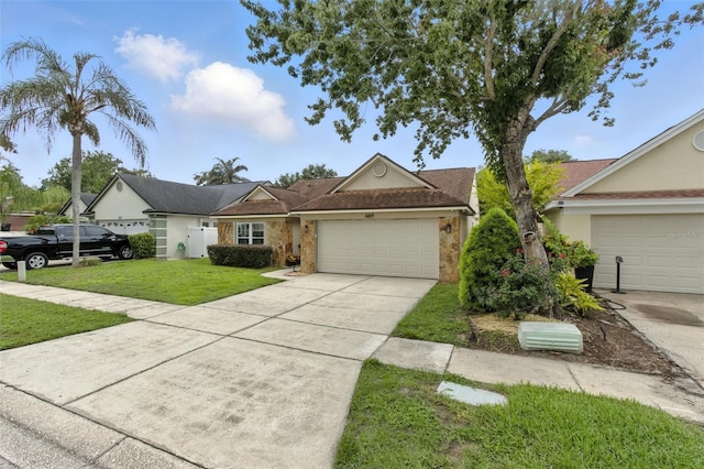 669 Whitetail Loop, Apopka, FL 32703 - view of front of property featuring an attached garage, driveway, a front yard, and stone siding