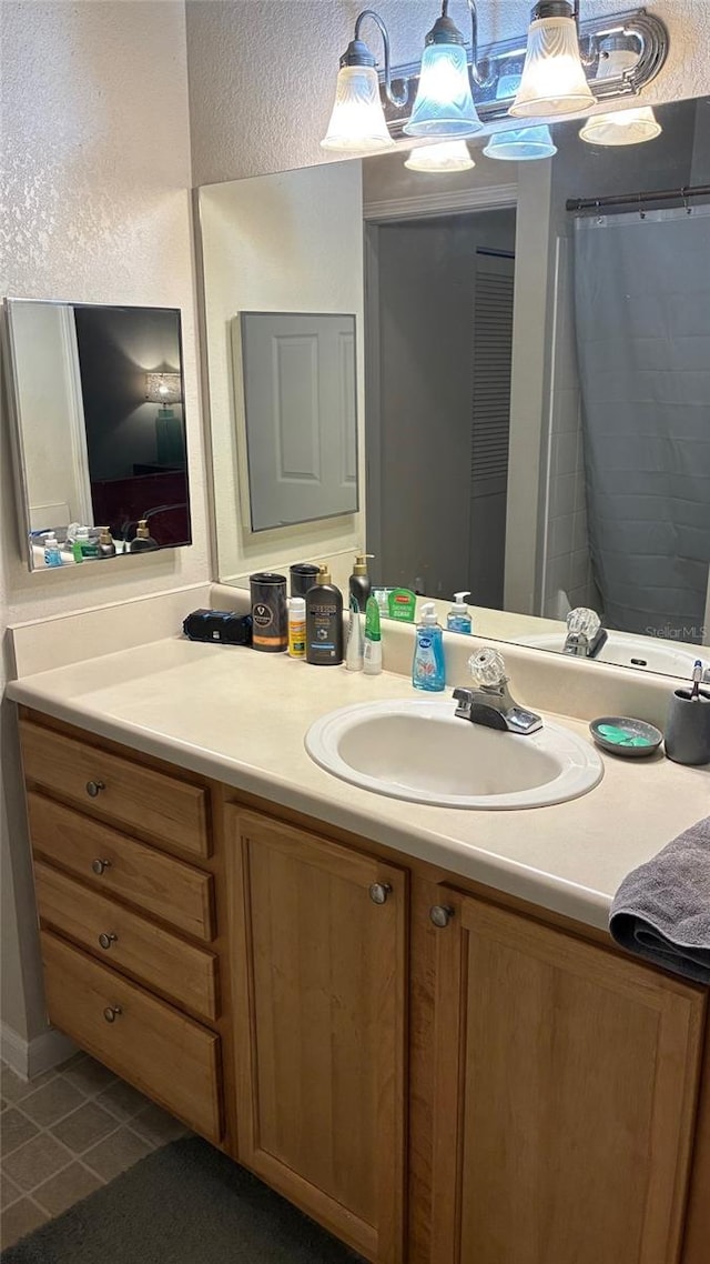 bathroom featuring vanity, tile patterned flooring, a textured wall, and curtained shower