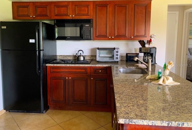 6336 Parc Corniche Dr, Orlando, FL 32821 - kitchen featuring black appliances, light tile patterned floors, and light stone counters