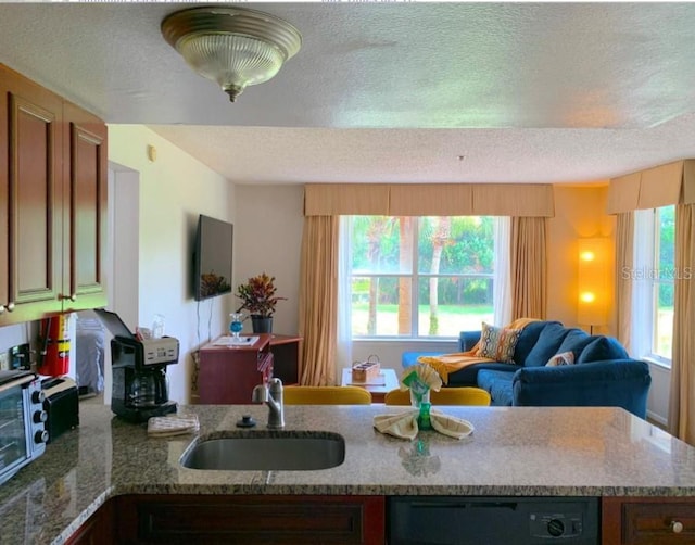 6336 Parc Corniche Dr, Orlando, FL 32821 - kitchen featuring a textured ceiling, open floor plan, black dishwasher, plenty of natural light, and light stone counters