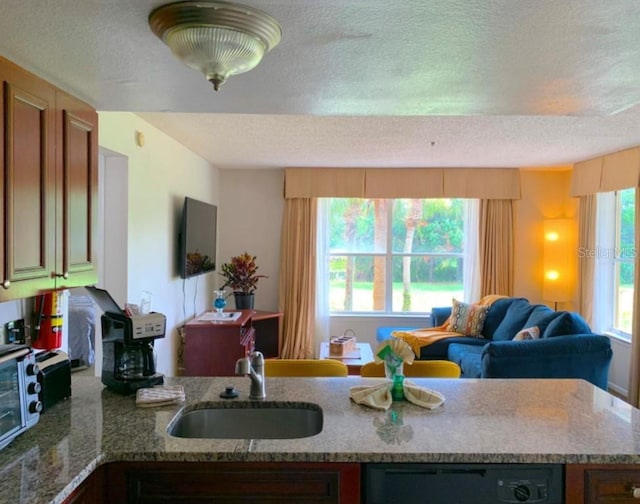 6336 Parc Corniche Dr, Orlando, FL 32821 - kitchen with a textured ceiling, open floor plan, light stone countertops, a peninsula, and brown cabinets