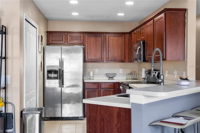 4027 Pemberly Pines Cir, Saint Cloud, FL 34769 - kitchen featuring stainless steel appliances, a peninsula, light countertops, light tile patterned flooring, and a kitchen bar