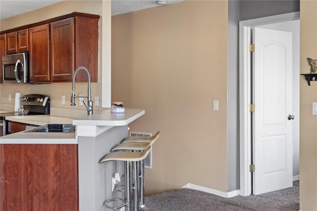 4027 Pemberly Pines Cir, Saint Cloud, FL 34769 - kitchen featuring stainless steel appliances, carpet floors, a kitchen breakfast bar, a peninsula, and light countertops
