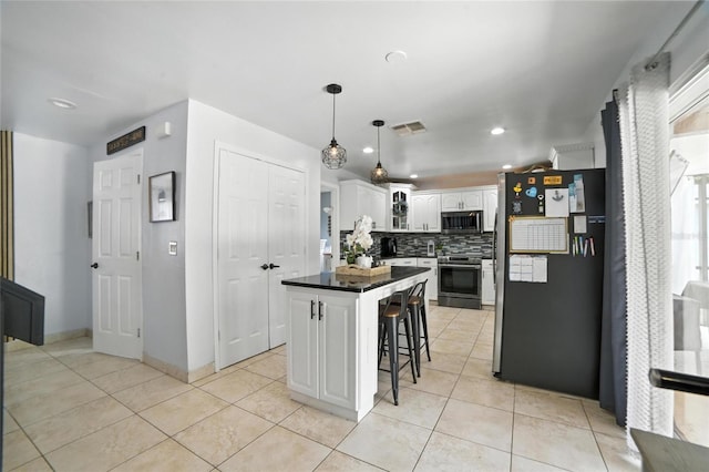 12419 Sion Ct, Orlando, FL 32824 - kitchen featuring stainless steel appliances, a center island, a breakfast bar, decorative backsplash, and white cabinetry
