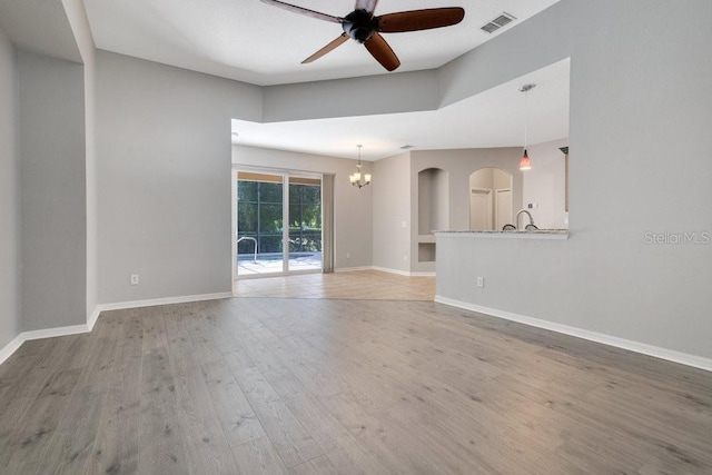 274 Wekiva Pointe Cir, Apopka, FL 32712 - unfurnished living room with a ceiling fan, light wood-style floors, a chandelier, and arched walkways