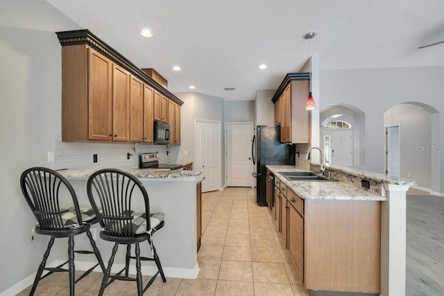274 Wekiva Pointe Cir, Apopka, FL 32712 - kitchen featuring a peninsula, black appliances, arched walkways, backsplash, and a breakfast bar