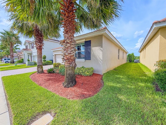 1047 Oak Bluff Dr, Davenport, FL 33837 - view of side of home with stucco siding, a yard, driveway, and a garage