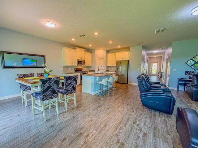 1047 Oak Bluff Dr, Davenport, FL 33837 - kitchen featuring stainless steel appliances, open floor plan, light wood finished floors, a textured ceiling, and white cabinetry