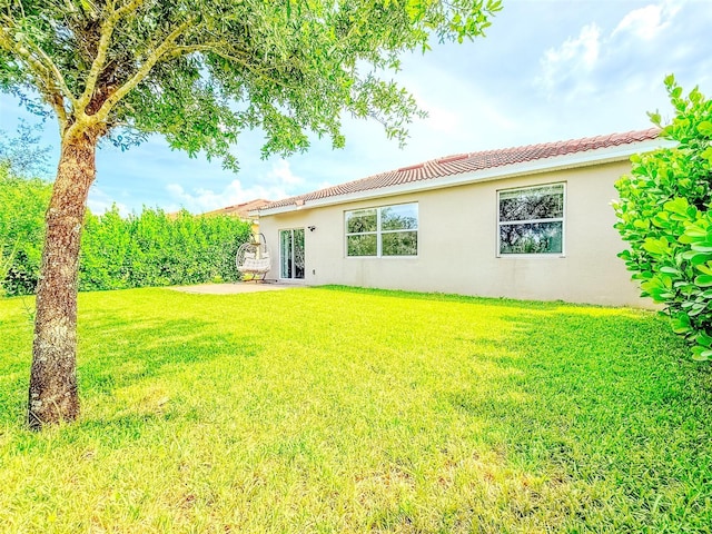 1047 Oak Bluff Dr, Davenport, FL 33837 - rear view of house with stucco siding, a lawn, and a tiled roof