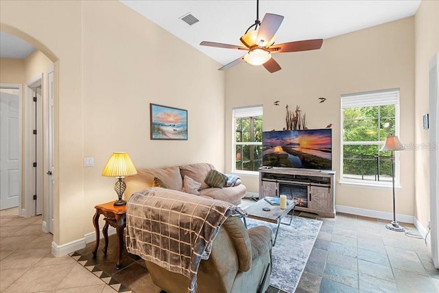 4080 Safflower Ter, Oviedo, FL 32766 - living area with arched walkways, ceiling fan, healthy amount of natural light, lofted ceiling, and a glass covered fireplace