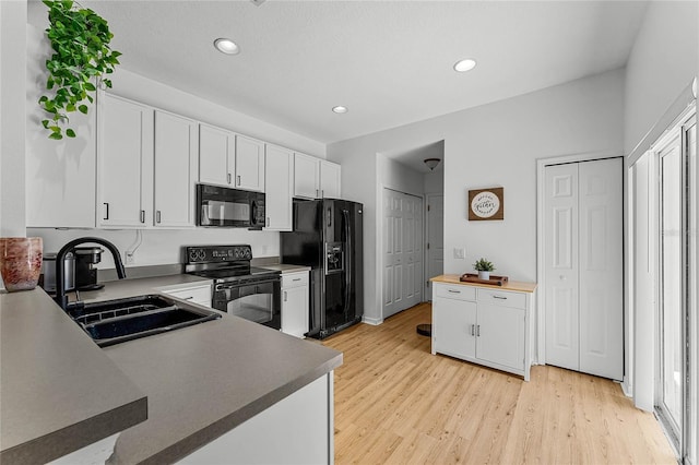 14466 Bridgewater Crossings Blvd, Windermere, FL 34786 - kitchen with black appliances, light wood-style floors, white cabinetry, and recessed lighting