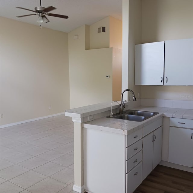 289 White Marsh Cir, Orlando, FL 32824 - kitchen with ceiling fan, tile countertops, a peninsula, and white cabinetry