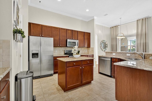 4060 Oak Tree Dr, Davenport, FL 33837 - kitchen featuring appliances with stainless steel finishes, crown molding, tasteful backsplash, a center island, and decorative light fixtures