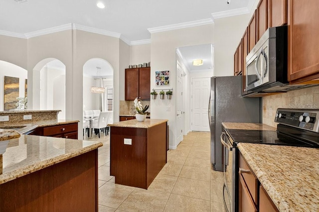 4060 Oak Tree Dr, Davenport, FL 33837 - kitchen with range with electric stovetop, stainless steel microwave, a center island, backsplash, and ornamental molding