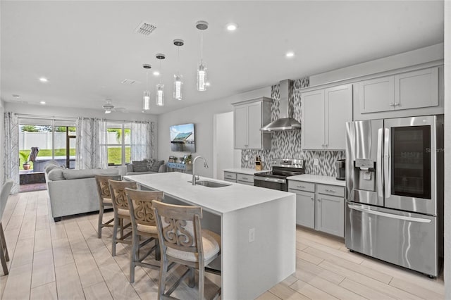 3336 Jackson Bluff Way, Clermont, FL 34711 - kitchen with stainless steel appliances, wall chimney range hood, gray cabinetry, light countertops, and a breakfast bar area