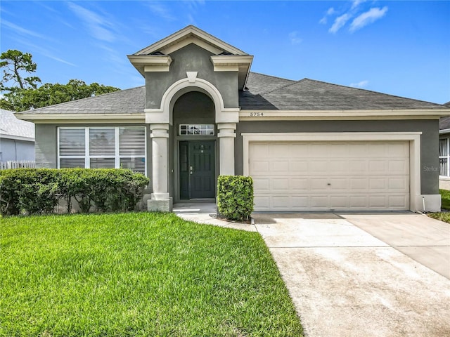 5754 Magnolia Bloom Ter, Oviedo, FL 32765 - view of front of home with a shingled roof, stucco siding, a front lawn, and a garage