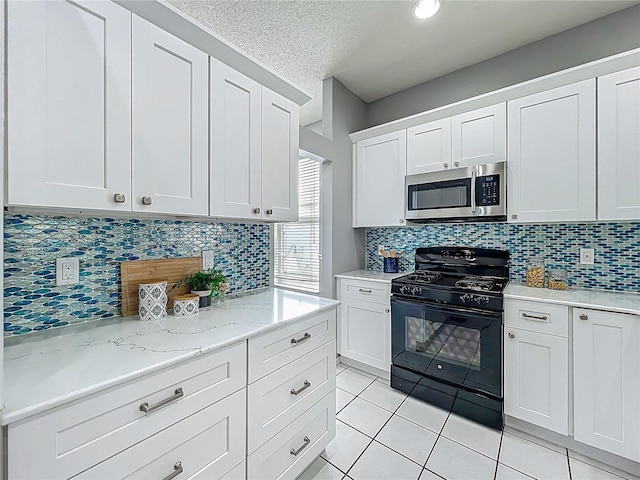 5754 Magnolia Bloom Ter, Oviedo, FL 32765 - kitchen featuring stainless steel microwave, black gas stove, light tile patterned floors, white cabinets, and a textured ceiling