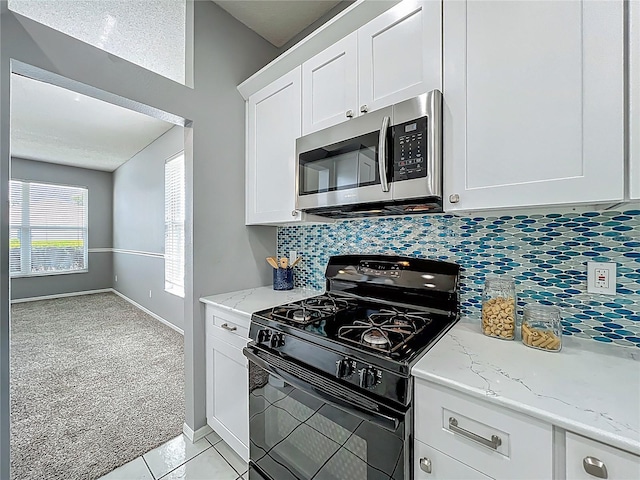5754 Magnolia Bloom Ter, Oviedo, FL 32765 - kitchen with black gas range oven, stainless steel microwave, light carpet, white cabinetry, and decorative backsplash