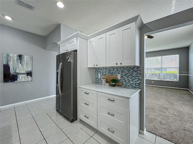 5754 Magnolia Bloom Ter, Oviedo, FL 32765 - kitchen with fridge with ice dispenser, light stone countertops, white cabinets, decorative backsplash, and light tile patterned floors