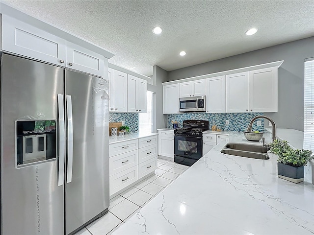 5754 Magnolia Bloom Ter, Oviedo, FL 32765 - kitchen featuring appliances with stainless steel finishes, decorative backsplash, a textured ceiling, white cabinets, and light stone counters