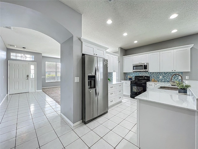 5754 Magnolia Bloom Ter, Oviedo, FL 32765 - kitchen with stainless steel appliances, white cabinetry, arched walkways, backsplash, and a textured ceiling