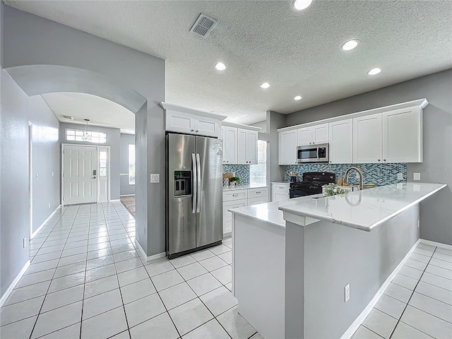 5754 Magnolia Bloom Ter, Oviedo, FL 32765 - kitchen featuring appliances with stainless steel finishes, a peninsula, light countertops, light tile patterned floors, and decorative backsplash