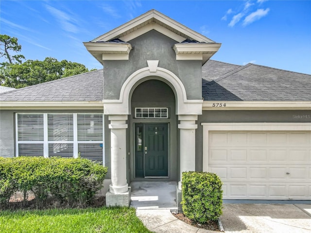 5754 Magnolia Bloom Ter, Oviedo, FL 32765 - entrance to property with roof with shingles, a garage, and stucco siding