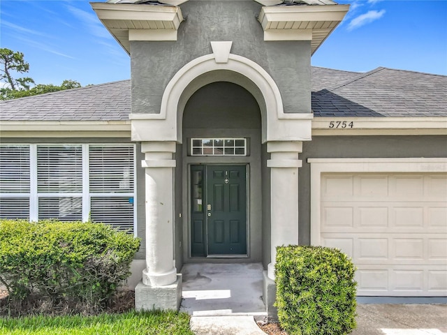5754 Magnolia Bloom Ter, Oviedo, FL 32765 - entrance to property with roof with shingles, an attached garage, and stucco siding