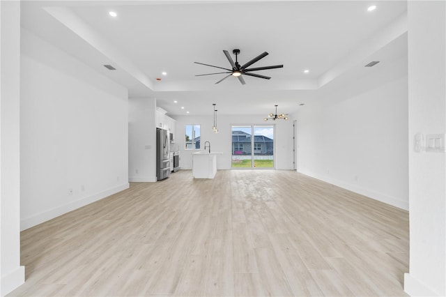 13438 Mcintosh Ave, Port Charlotte, FL 33981 - unfurnished living room with a raised ceiling, a chandelier, recessed lighting, light wood-style flooring, and a ceiling fan