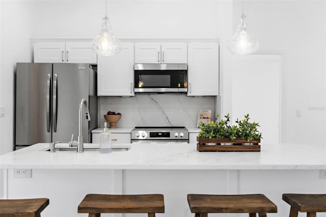 7450 Franzino Ave, North Port, FL 34291 - kitchen with appliances with stainless steel finishes, white cabinets, pendant lighting, tasteful backsplash, and a kitchen bar