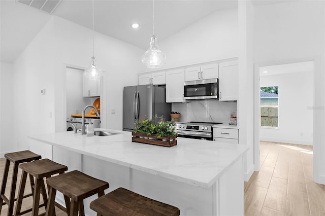 7450 Franzino Ave, North Port, FL 34291 - kitchen with appliances with stainless steel finishes, white cabinetry, an island with sink, a kitchen bar, and hanging light fixtures