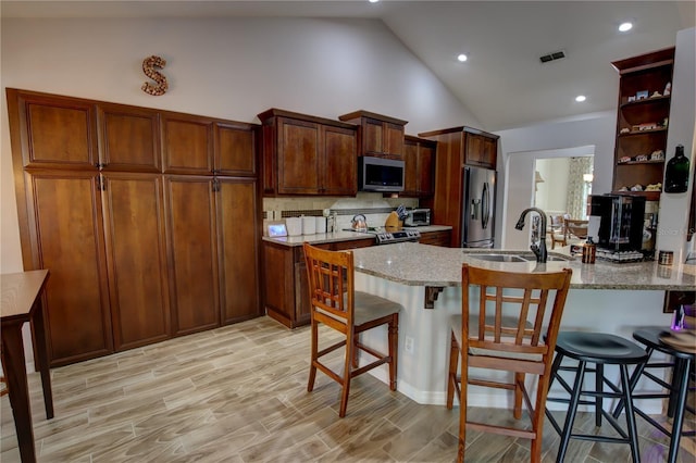 1624 Bear Crossing Cir, Apopka, FL 32703 - kitchen with stainless steel appliances, a peninsula, open shelves, light stone countertops, and a kitchen bar