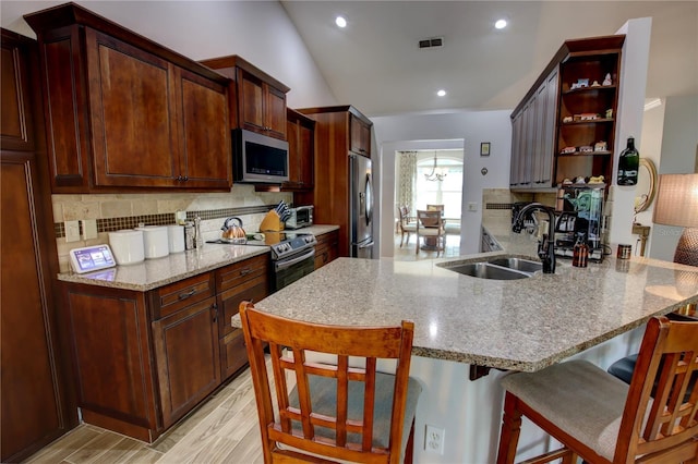 1624 Bear Crossing Cir, Apopka, FL 32703 - kitchen with appliances with stainless steel finishes, open shelves, a peninsula, backsplash, and a kitchen breakfast bar