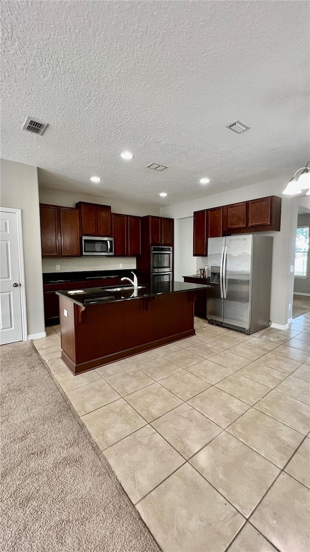 8625 Coventry Park Way, Windermere, FL 34786 - kitchen featuring stainless steel appliances, dark countertops, recessed lighting, a textured ceiling, and a center island with sink