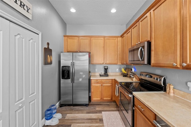 962 Ashworth Overlook Dr Unit C, Apopka, FL 32712 - kitchen with appliances with stainless steel finishes, wood finished floors, light countertops, a textured ceiling, and recessed lighting