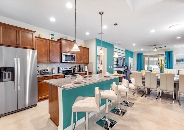 8874 Qin Loop, Kissimmee, FL 34747 - kitchen with appliances with stainless steel finishes, tasteful backsplash, a center island with sink, recessed lighting, and a kitchen breakfast bar